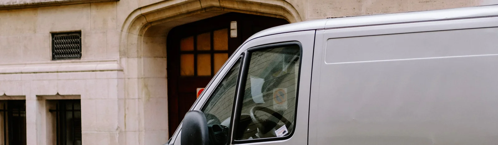 A long-wheelbase courier van parked on a historic town street.